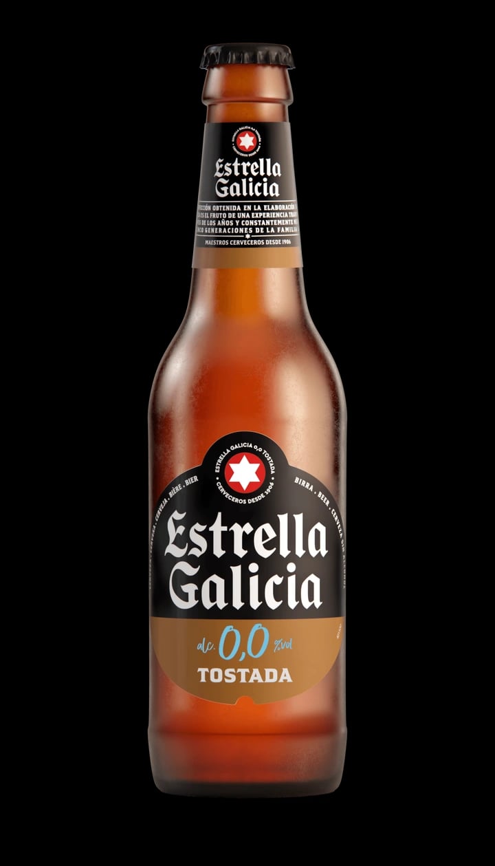 Dark amber Estrella Galicia 0.0 Tostada non-alcoholic beer with orange reflections showcasing its toasted malt character